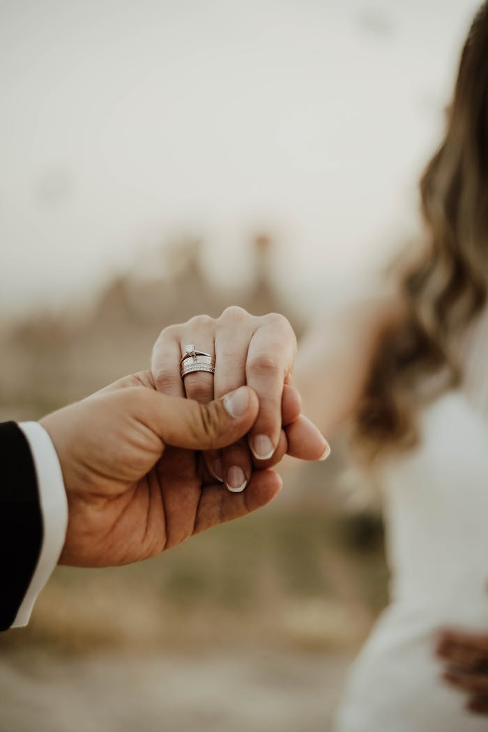 Romantic close-up of bride and groom holding hands during their wedding ceremony.