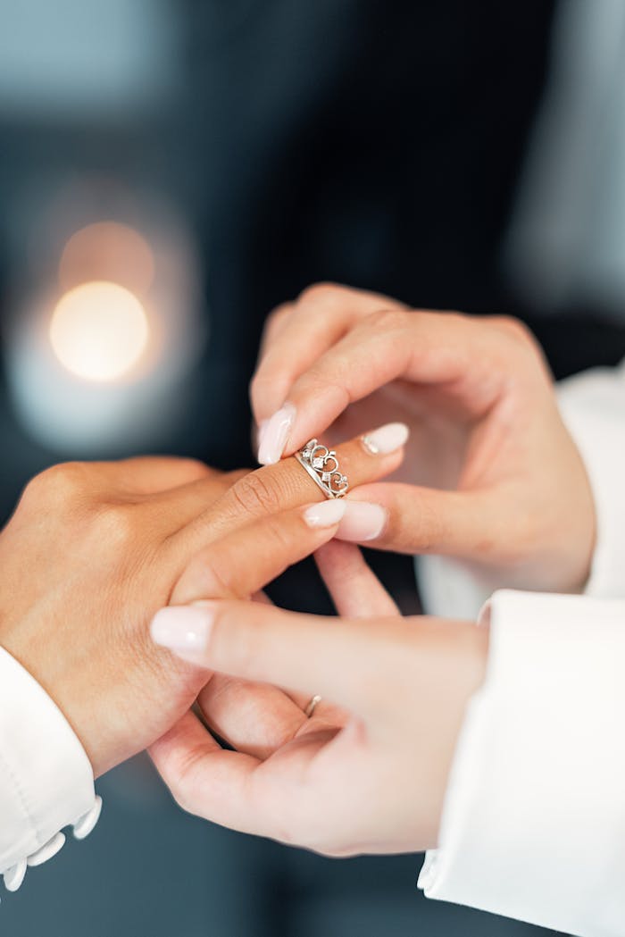 A detailed shot of two people exchanging wedding rings, symbolizing love and commitment.